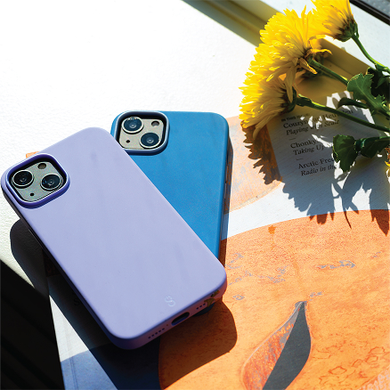 Two colourful LOGiiX phone cases placed on a table with sunlight and flowers.