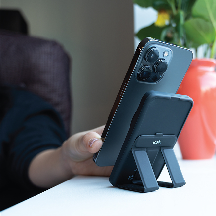 Smartphone positioned on a stand while a person uses the device.